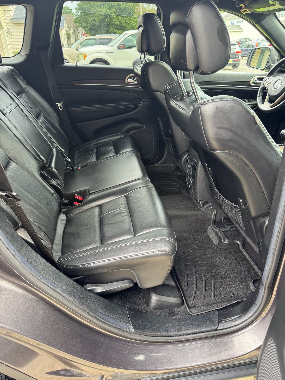 Jeep Grand Cherokee rear interior after detailing — clean black leather bench and spotless all-weather floor mat.